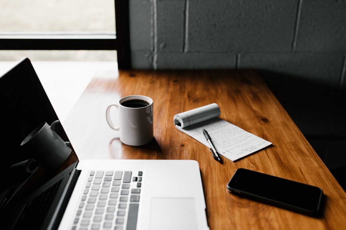 Laptop, Notepad and cup of coffee resting on a desk